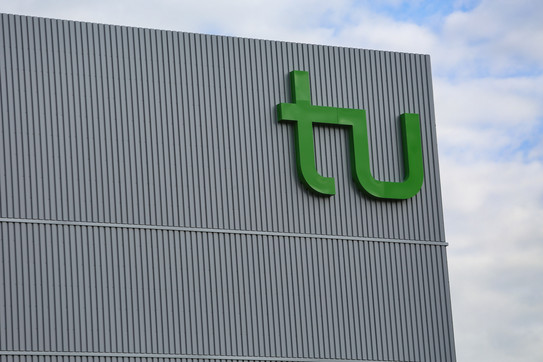 The green logo of TU Dortmund University on a building.